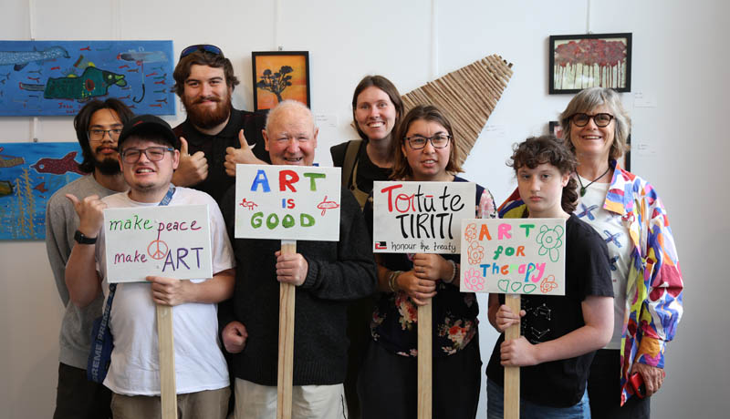 Artists from Artists in the Making holding signs about the benefits of the arts